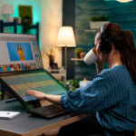 Woman with editor occupation wearing headphones at studio office desk. Professional graphic artist working on picture editing background for template using touchpad monitor screen